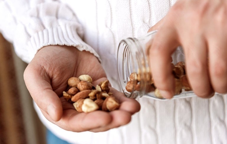 Man pouring out mixed nuts to get plant-based proteins on the Flexitarian Diet