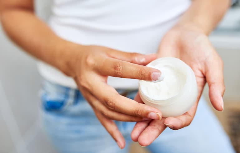 Woman holding a new moisturizer, which may cause skin purging