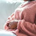 Woman clutching her stomach in pain because she's menstruating and suffering from the pains of period poops