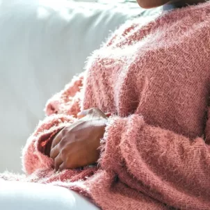 Woman clutching her stomach in pain because she's menstruating and suffering from the pains of period poops