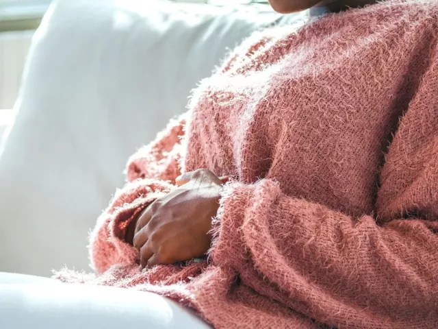 Woman clutching her stomach in pain because she's menstruating and suffering from the pains of period poops