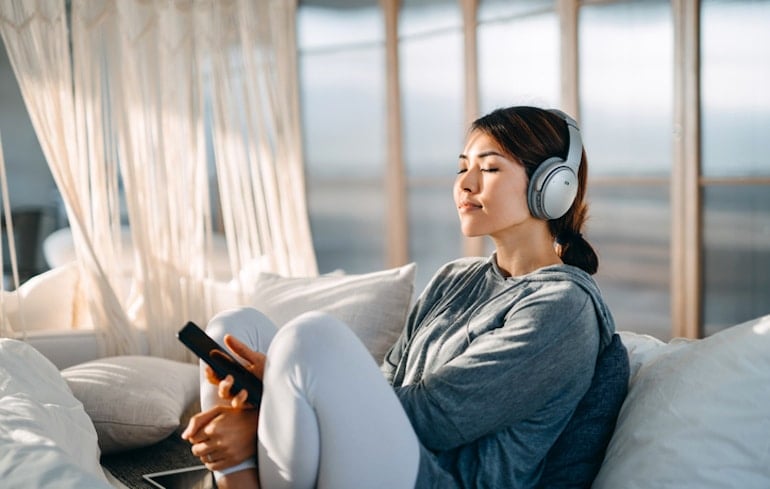 Woman listening to music for less stress and its calming benefits