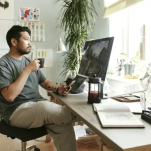 Man drinking French press coffee at his desk, wondering if coffee makes you bloated