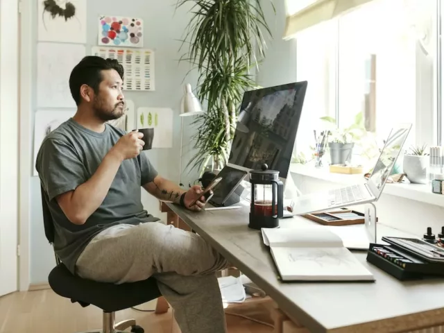 Man drinking French press coffee at his desk, wondering if coffee makes you bloated