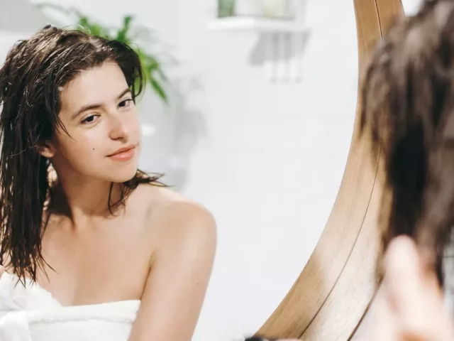 Woman spraying rice water into her hair to help it grow, according to the viral DIY hair trend