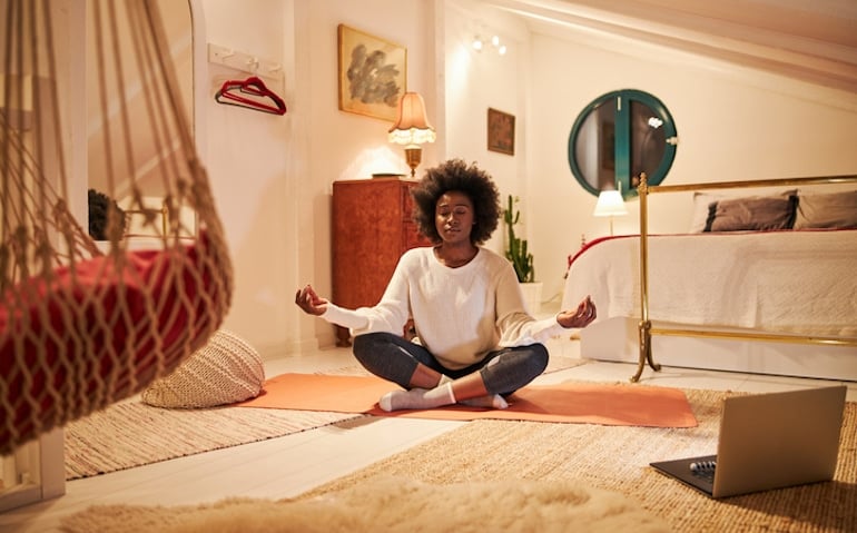 Woman meditating at home to reduce stress and alleviate period poops through mindful self-care