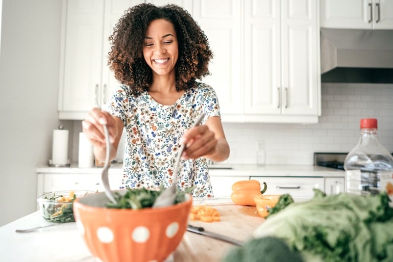 Woman mixing a salad with lettuce and dark leafy greens