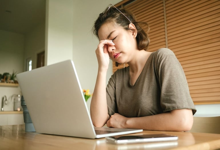 Woman working at table stressed out, soon experiencing period poops and digestive issues