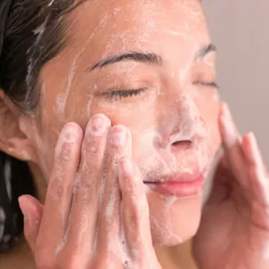 Woman washing her face and following sustainable skincare tips for environmental concerns