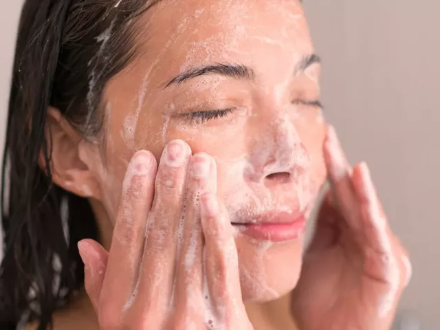 Woman washing her face and following sustainable skincare tips for environmental concerns