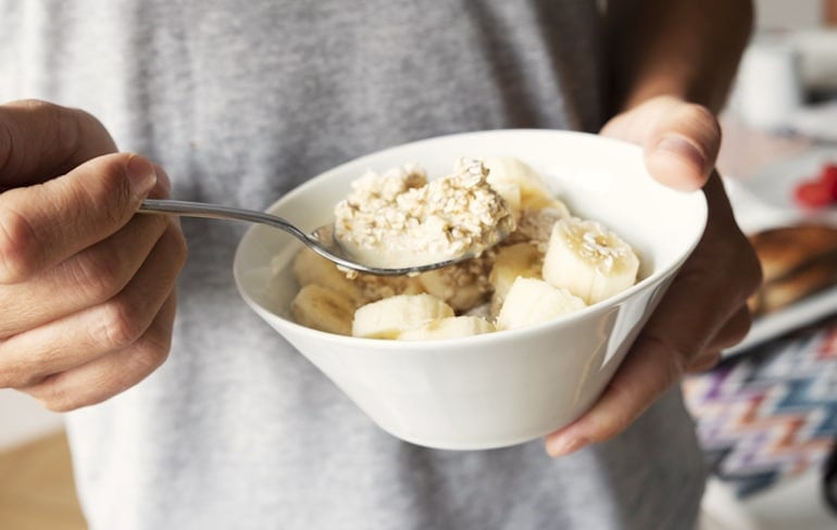 Man eating fiber-rich porridge with potassium-rich bananas for relief from bloating