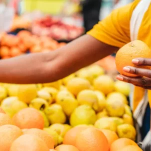 Woman buying citrus fruits at the farmers market as one method to eat more sustainably