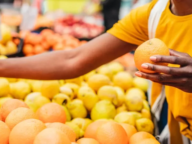 Woman buying citrus fruits at the farmers market as one method to eat more sustainably