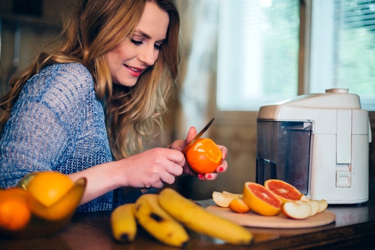 Woman peeling oranges for juicing to experience the benefits of vitamin C for her dull, dry skin