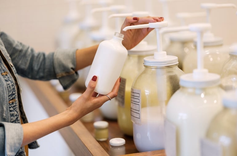 Woman refilling her empty glass bottle with beauty products at her local apothecary