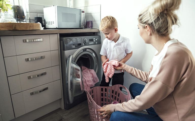 Mom doing laundry with her young son, supported by vitamin B5 and B6 supplementation for lasting energy