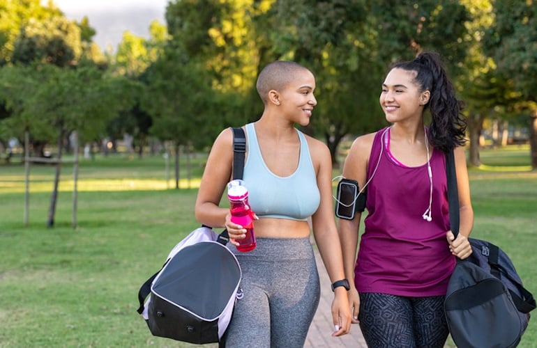 Two female friends walking in the park to get light exercise to help stop period pain naturally