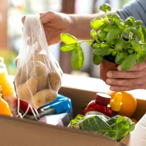 Man unpacking his grocery haul with plant-based foods, rich in benefits for human and environmental health
