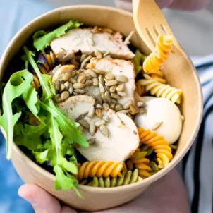 Eating a bowl with chicken and sunflower seeds, two of the best foods to eat for hair growth