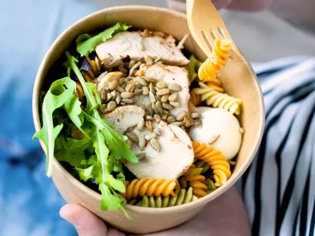 Eating a bowl with chicken and sunflower seeds, two of the best foods to eat for hair growth