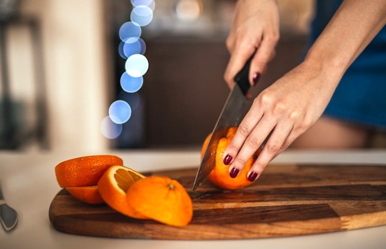 Woman slicing orange to reach her vitamin C intake for immunity