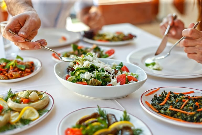 Doctor eating family style, reaching for a salad portion to keep a healthy immune system