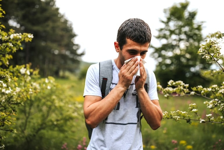 Man blowing his nose outdoors to protect himself from pollen and other antigens, illustrating how the immune system works