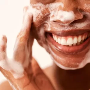 Woman smiling while double cleansing her face
