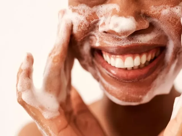 Woman smiling while double cleansing her face