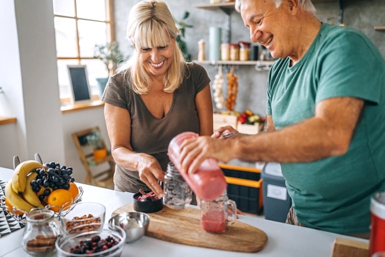 how do nutritional needs change over time? Married couple in their 60s making a vitamin C smoothie to stay healthy with antioxidants and prevent skin aging