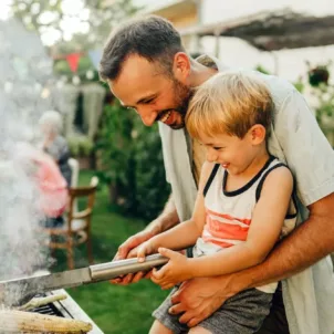 Father sharing grilling tips with his son at family barbecue