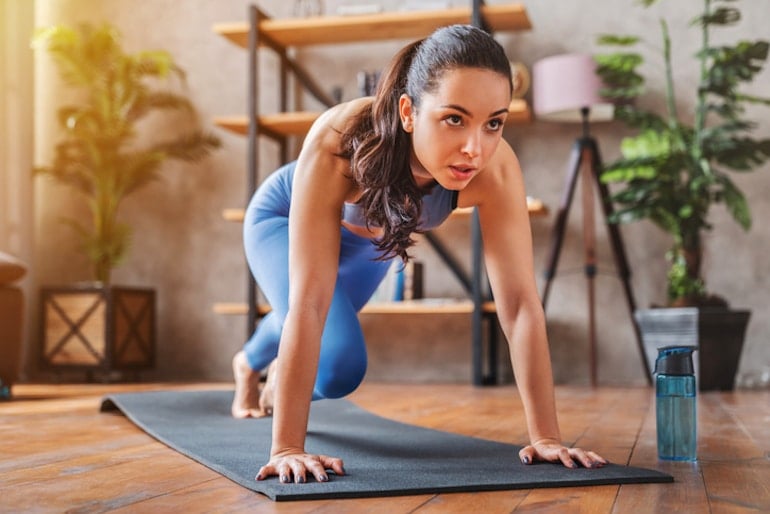 Woman doing yoga at home and staying hydrated with water