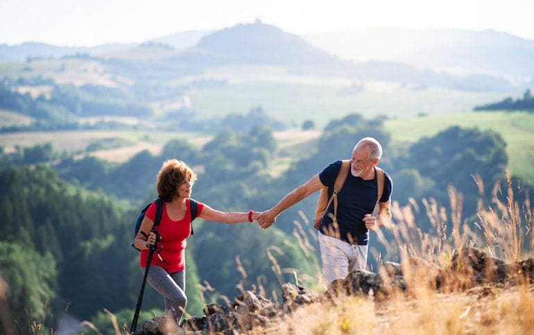 Senior couple holding hands while hiking, which can strengthen relationships and bonding