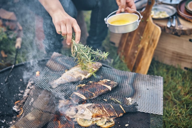 Man grilling fish over a campfire