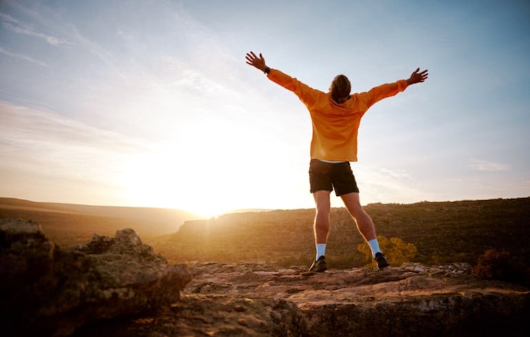 Man celebrating reaching the top of a summit, demonstrating a mental health benefit of hiking