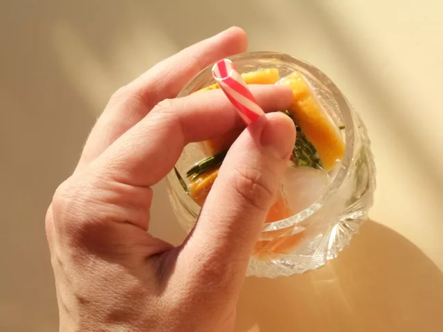 Holding onto straw in seltzer glass with fruits