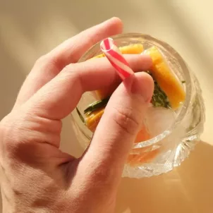 Holding onto straw in seltzer glass with fruits