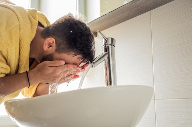 Man washing his face with an activated charcoal cleanser to remove oil and refine pores