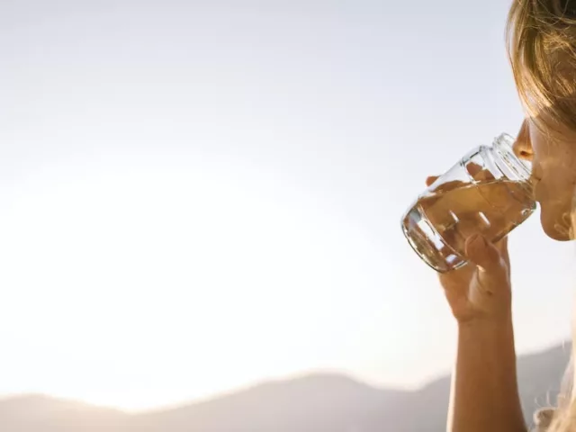 Woman taking supplements with water to address her summer beauty and wellness concerns