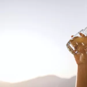 Woman taking supplements with water to address her summer beauty and wellness concerns