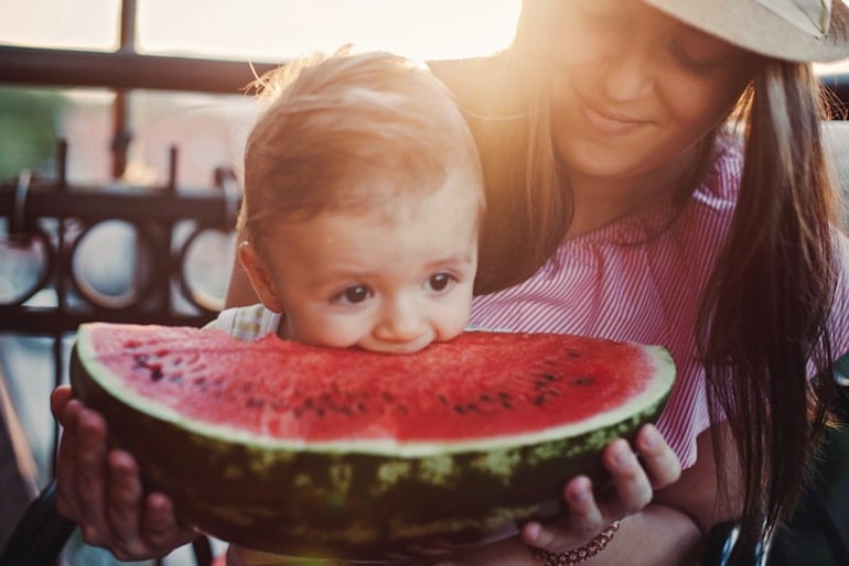 Mother and baby eating watermelon for their health benefits