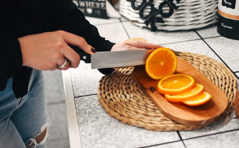 Woman slicing oranges to promote healthy hair growth