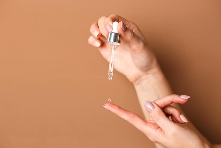 Woman applying PHA serum from a dropper