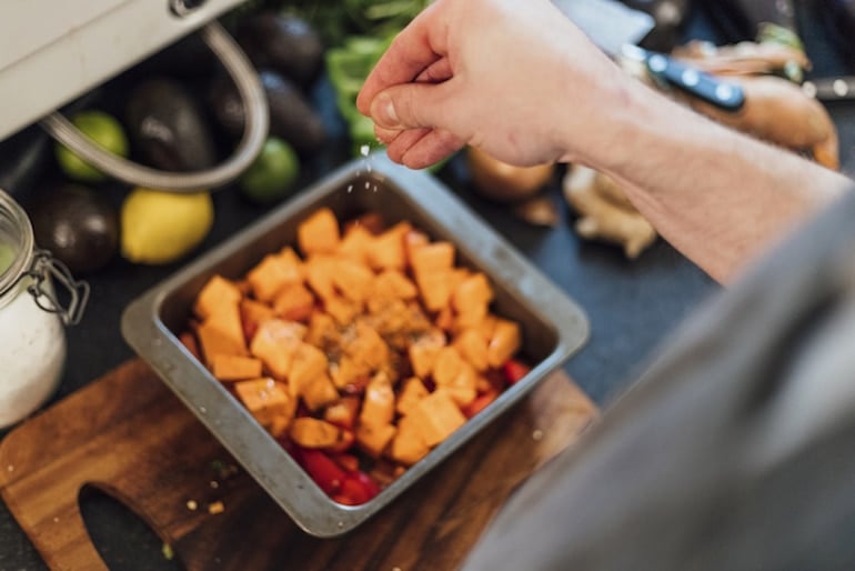 Man seasoning sweet potatoes, which are among the best foods for nail growth