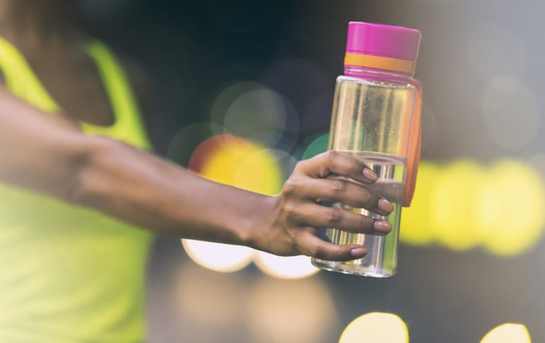 Athletic woman holding a water bottle, showing off her strong nails