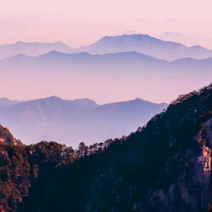 Mountain in a purple/pink sky landscape for summery wellness horoscopes concept