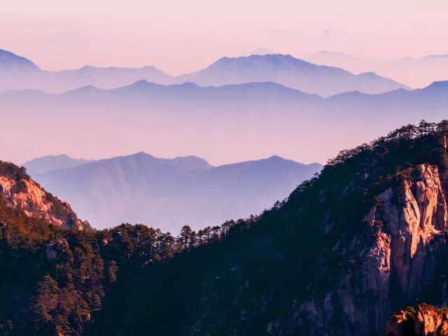 Mountain in a purple/pink sky landscape for summery wellness horoscopes concept