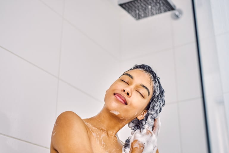 Woman washing hair under shower head filter