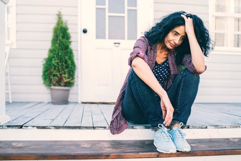 Postmenopausal women sitting in discomfort on stoop