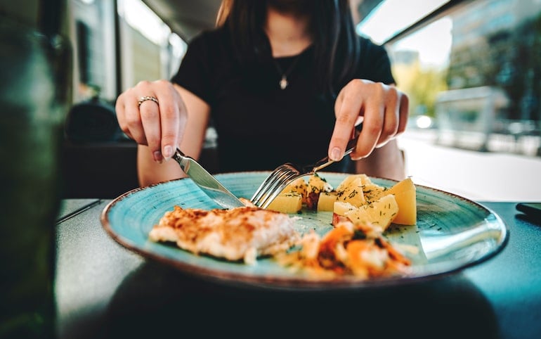 Woman with long nails cutting chicken, which is one of the best foods for nails